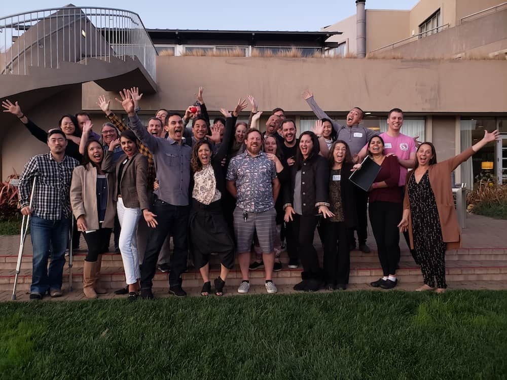 A cheerful group A cheerful group of participating couples and therapists cheering together outdoors at the Love Made Simple workshop retreat.
