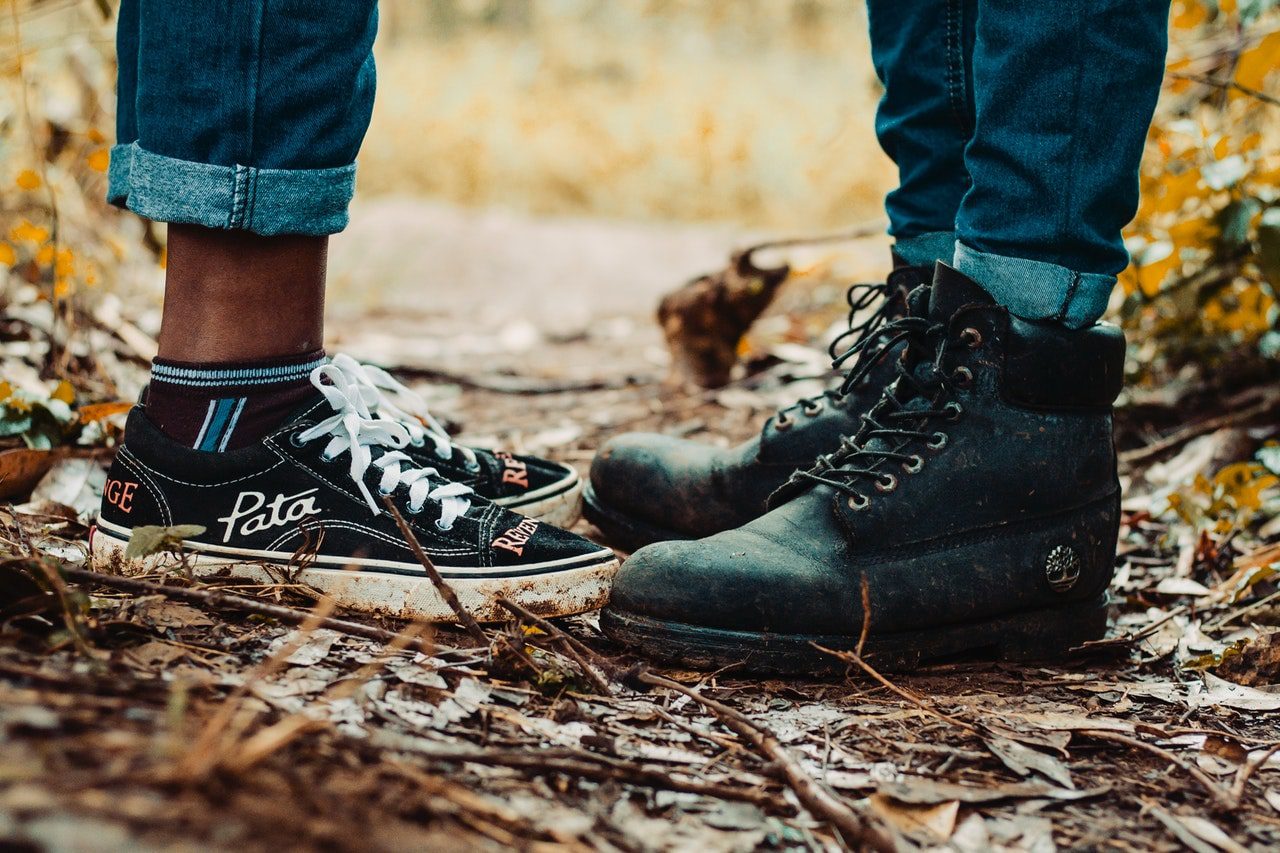 Close-up of a couple standing face-to-face on a outdoor path, wearing black sneakers and dark work boots