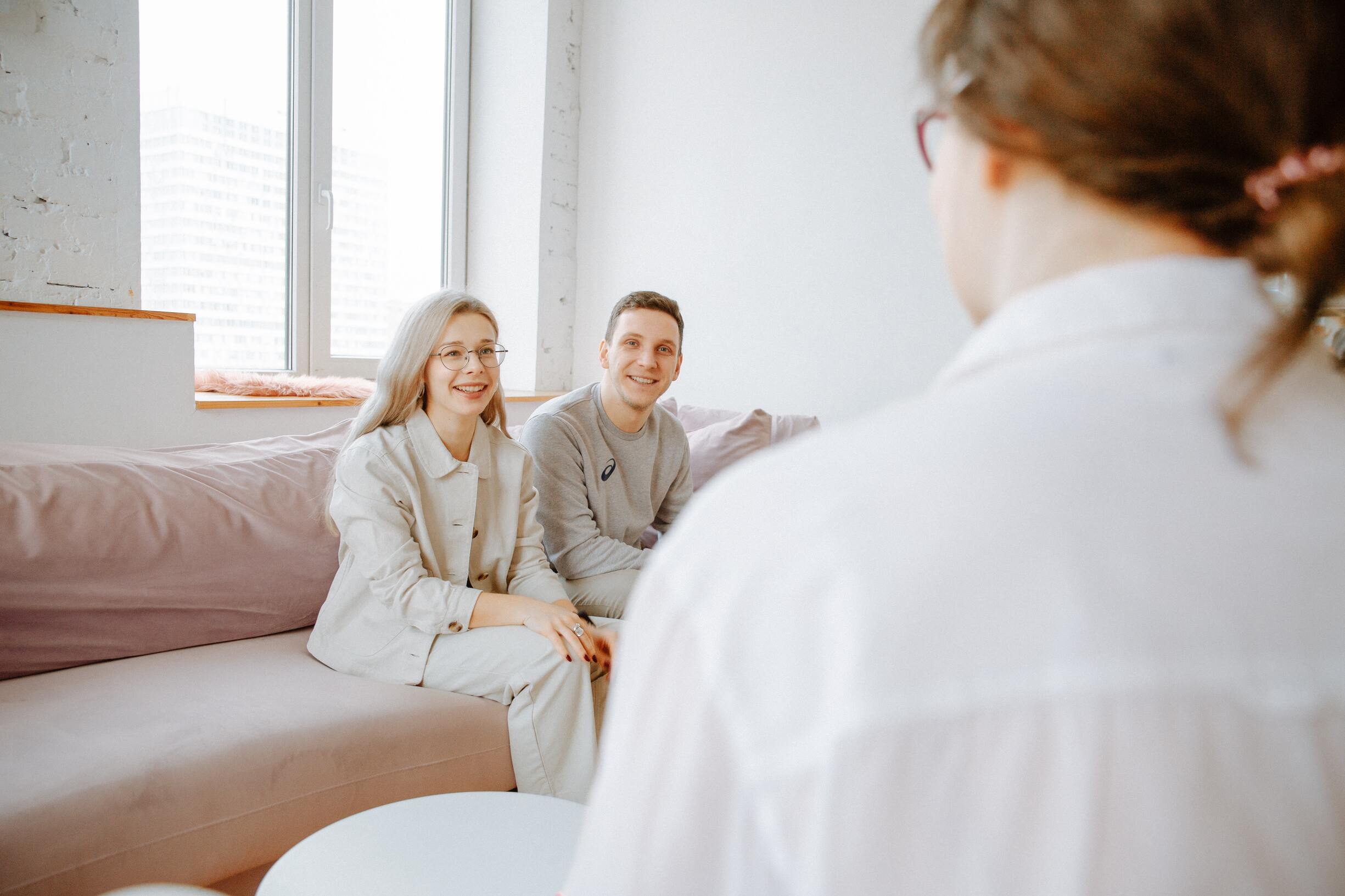 Young couple smiling while speaking with a therapist during a couples therapy session discussing insurance coverage
