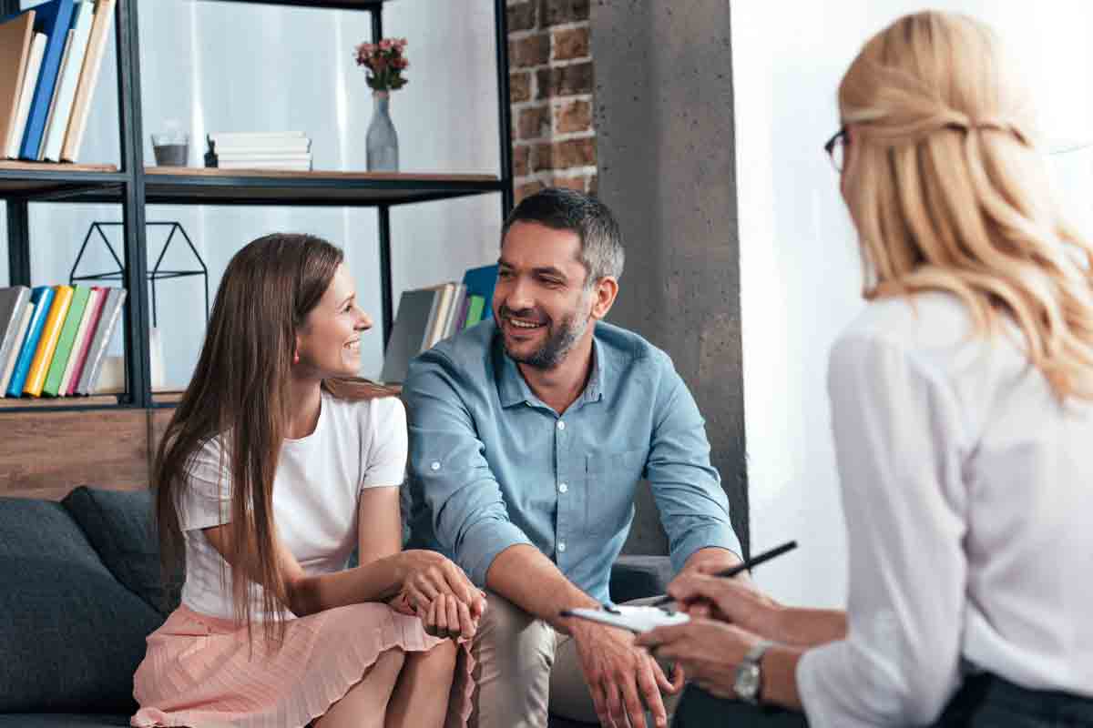 Happy couple holding hands and smiling during a relationship therapy session