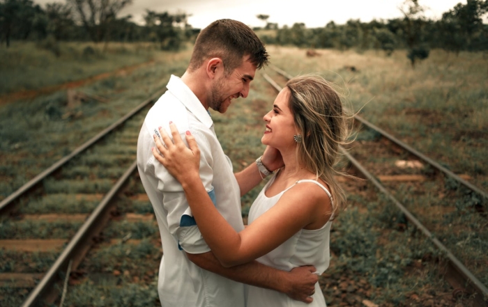 A happy couple embracing and smiling together outdoors, symbolizing trust and open communication to overcome money issues in marriage.