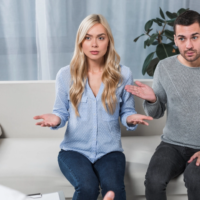 Frustrated couple gesturing with open hands while speaking with a therapist during a couples counseling session