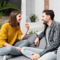 Happy couple sitting cross-legged on a couch having an open, positive conversation