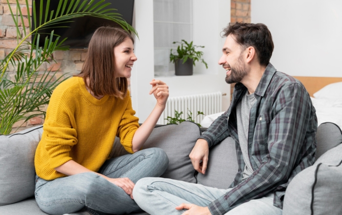 Happy couple sitting cross-legged on a couch having an open, positive conversation
