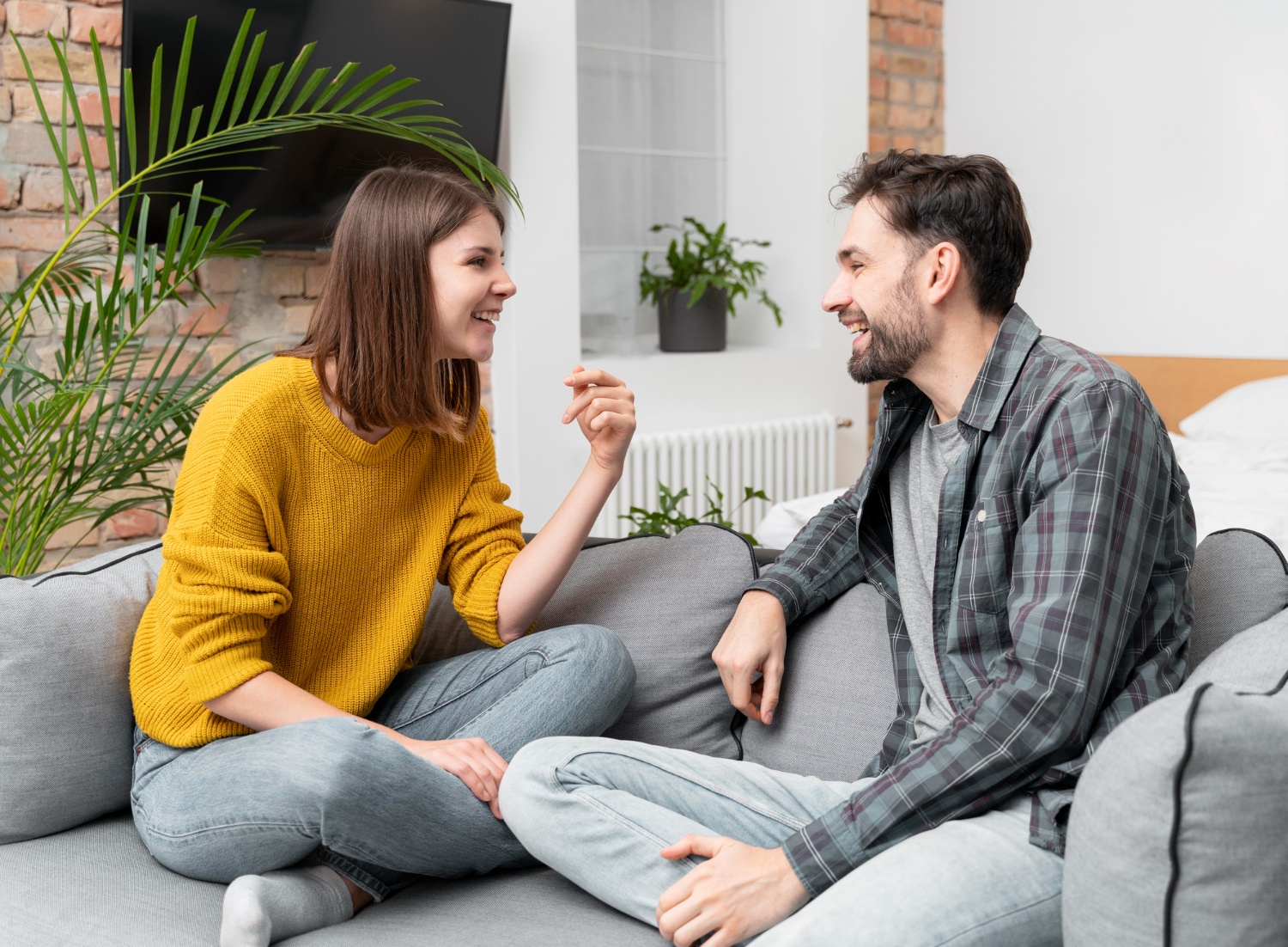 Happy couple sitting cross-legged on a couch having an open, positive conversation