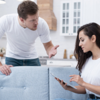 An angry man arguing while a woman ignores him using a tablet.