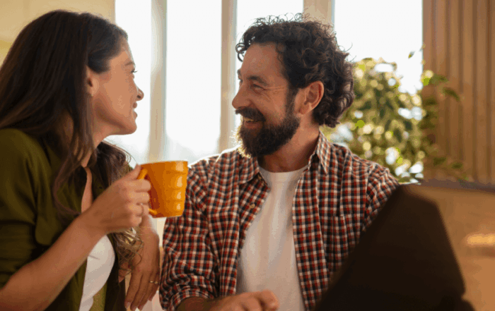 Smiling bearded man looking at his partner holding a yellow mug during a conversation.