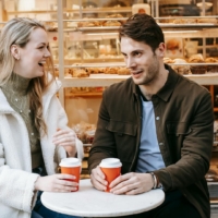 Smiling couple chatting over coffee outside a bakery during a romantic date