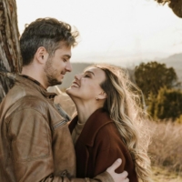 A couple embracing affectionately while looking into each other's eyes in a scenic outdoor setting.
