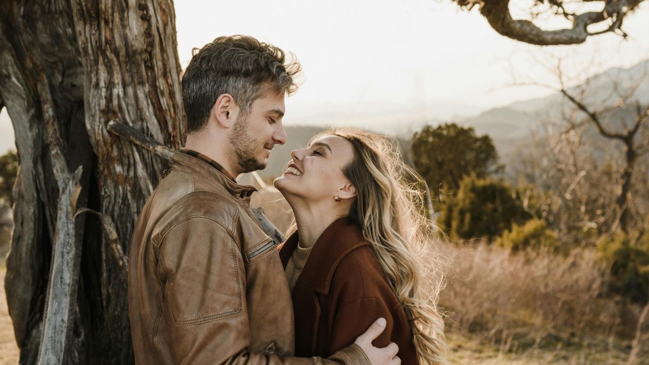 A couple embracing affectionately while looking into each other's eyes in a scenic outdoor setting.